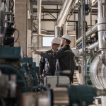Mina a céu aberto com equipamentos industriais e estrutura de processamento ao fundo, representando a exploração de minerais estratégicos