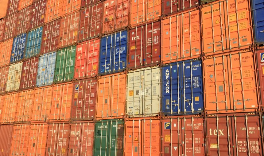 Contêineres coloridos empilhados em um porto, representando operações de transporte e comércio internacional.